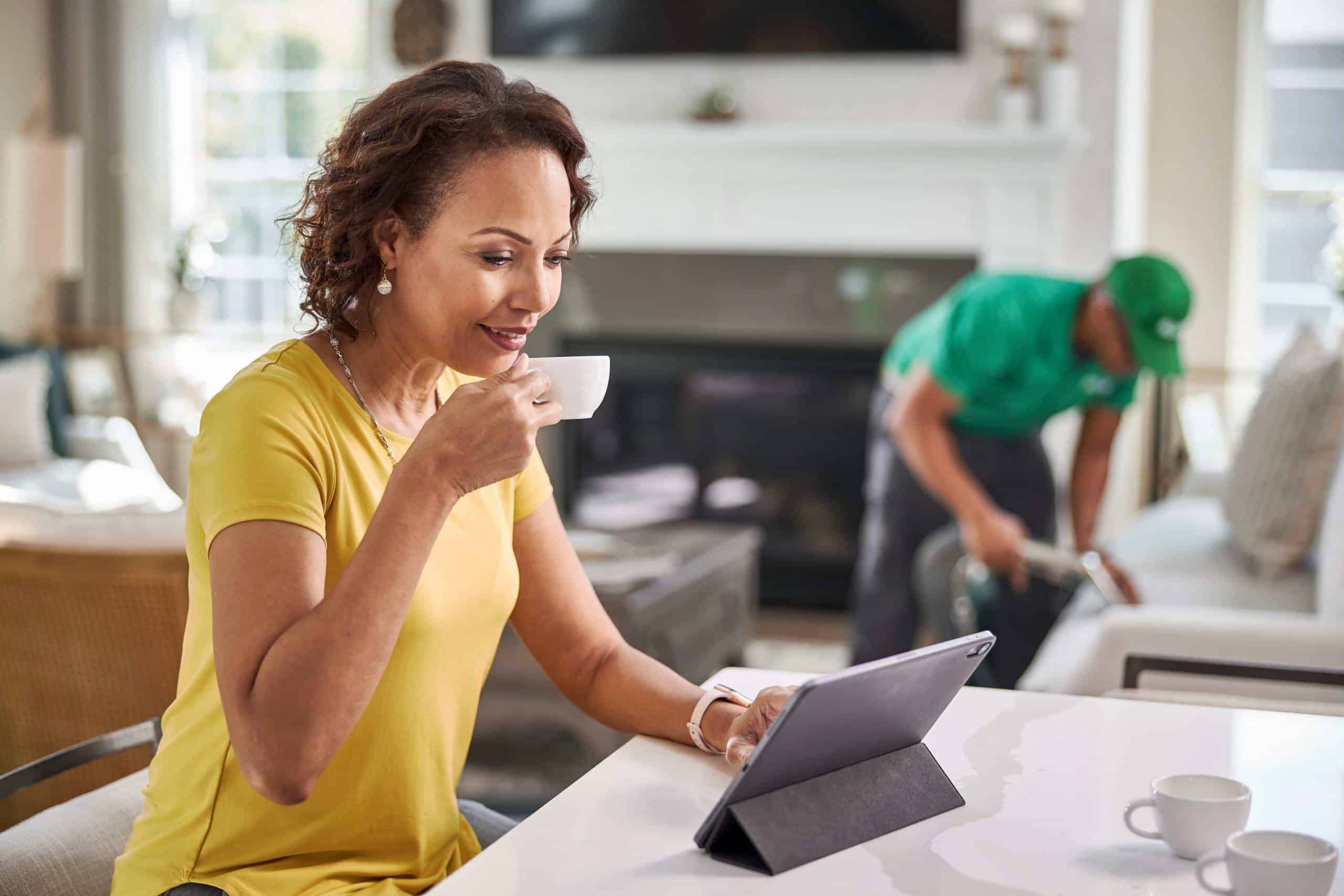 Fresh coffee in hand, woman enjoys a moment while carpet cleaning service is performed indoors in Kansas City.